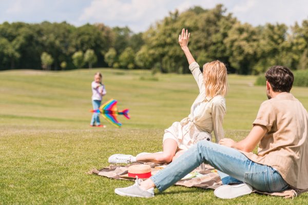 Young family enjoying a sunny picnic, playing with children in a garden.
