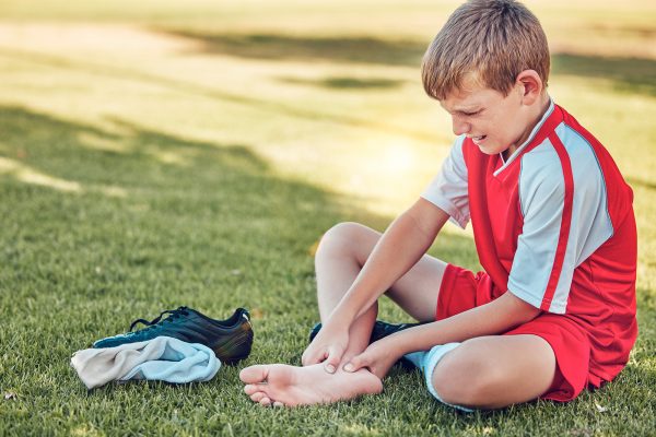 https://elements.envato.com/soccer-injury-and-pain-of-child-foot-on-field-cry--EFYSVTZ ALT TEXT: Young boy sitting on the grass holding his foot in pain after playing soccer, showing signs of foot discomfort or injury